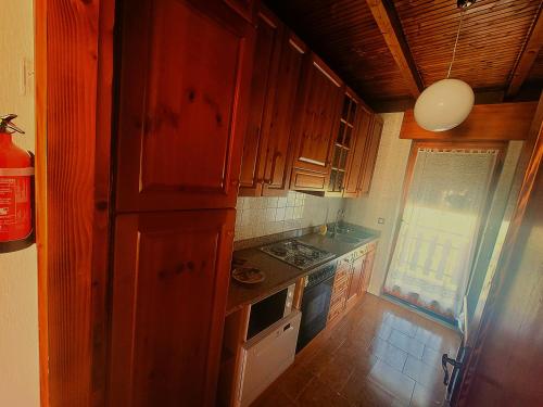 a small kitchen with wooden cabinets and a window at Cuore d'Altopiano, vivere Asiago in Asiago