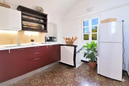 a kitchen with red cabinets and a white refrigerator at The Old Ship in Costarainera