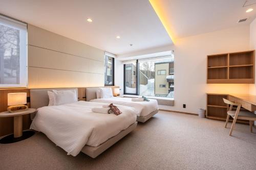 2 letti in una camera con scrivania e 2 finestre di V Residence by H2 Life a Niseko
