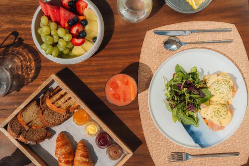 un tavolo con due piatti di cibo e un cesto di frutta di Cali Mykonos a Kalafatis