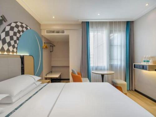 ein Schlafzimmer mit einem großen weißen Bett und einem Tisch in der Unterkunft City Comfort Inn Kunming Railway Station Guanshang in Kunming
