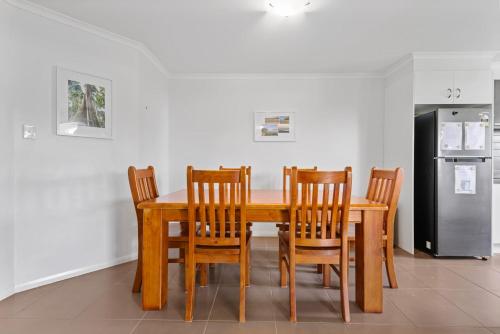 a wooden dining room table with chairs and a refrigerator at Charming 3-Bed Home Near Sunshine Coast in Caloundra West