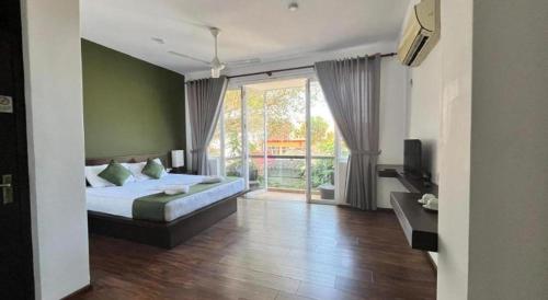 a bedroom with a bed and a large window at Lavinia Villa in Karagampitiya