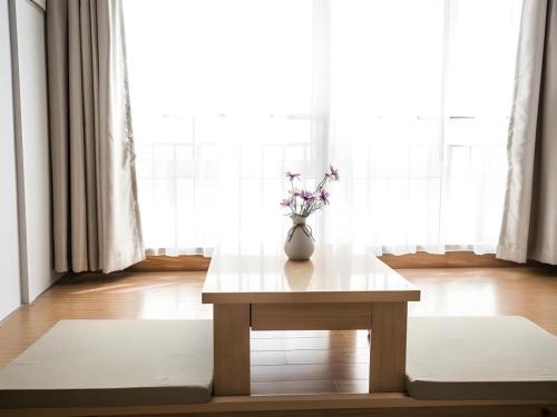 een vaas met bloemen op een tafel voor een raam bij GreenTree Inn Suqian Suyu District Red Star Macalline in Zhuoxu