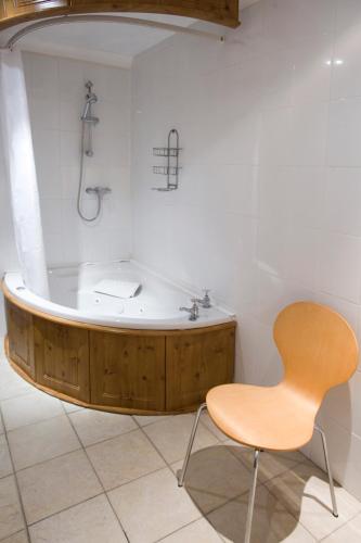 a bath tub with a wooden chair in a bathroom at Bourne Hall Country Hotel in Shanklin