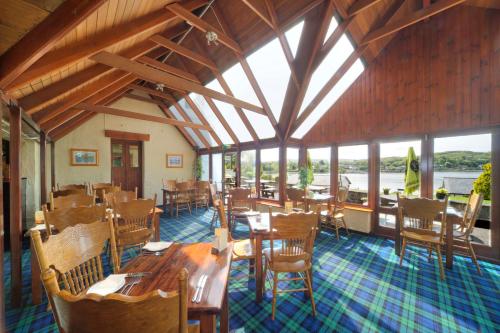 a restaurant with wooden tables and chairs and windows at Lochnell Arms Hotel in Oban