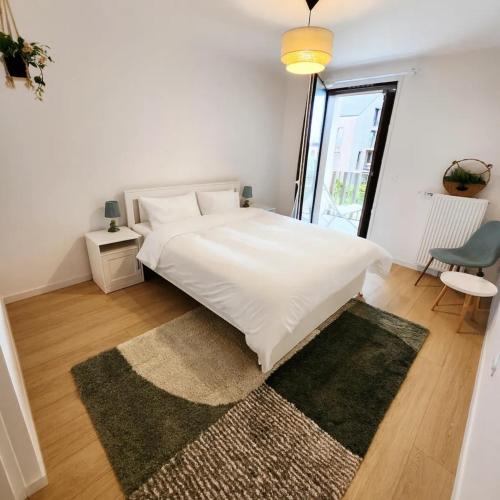 a bedroom with a large white bed with a rug at Élégant appartement lumineux à Senlis in Senlis
