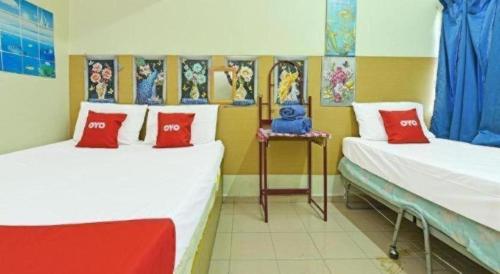 een kamer met 2 bedden met rode en witte kussens bij SPOT ON 90625 Super Green Grass Hotel in Yong Peng