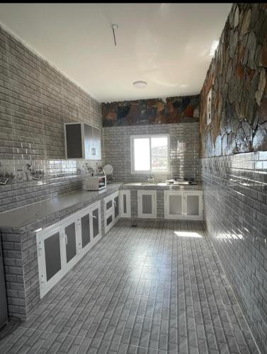 a large kitchen with a brick wall at Climbing Guest House Jebel Shams in Dār Sawdāʼ