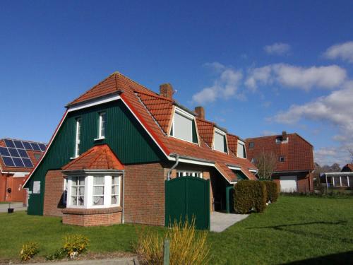 une maison avec un toit vert sur une cour dans l'établissement Terraced house, Friedrichkoog-Spitze, à Friedrichskoog-Spitz