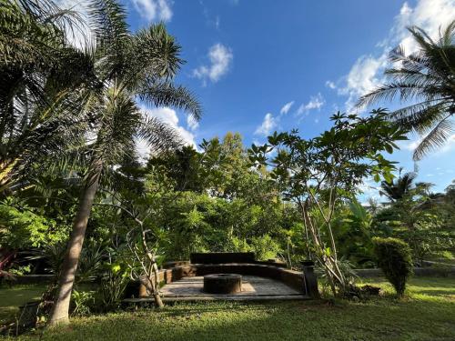 a park with a bench and some palm trees at Mojosurf Red Island in Pulau Lutung