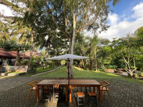 a wooden table with an umbrella in a park at Mojosurf Red Island in Pulau Lutung
