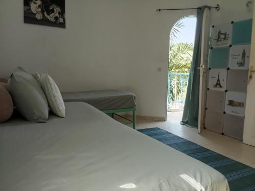 a bedroom with a white bed and a window at Charming duplex - Villa Bleue Majorelle, Saly in Saly Portudal