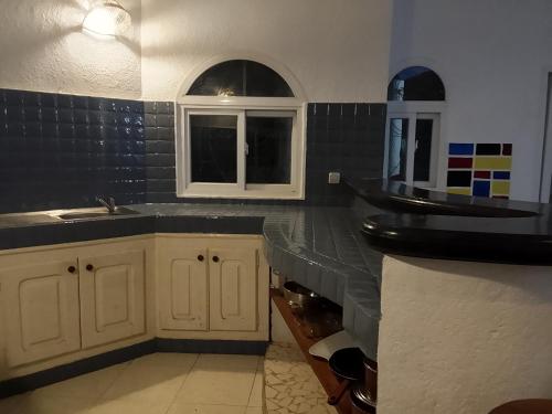 a kitchen with white cabinets and a sink and a window at Charming duplex - Villa Bleue Majorelle, Saly in Saly Portudal