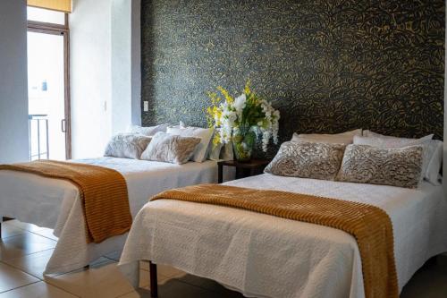 CedroOYO Hotel Casa Zaragoza的一间卧室配有两张带白色床单和鲜花的床。