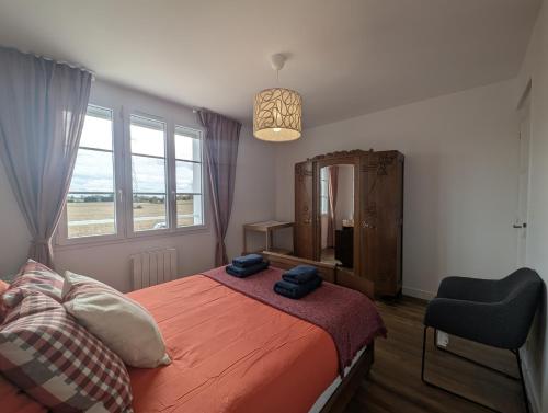 a bedroom with a bed and a chair and a window at La Maison des Vergers in Teloché