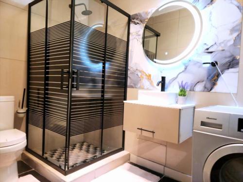 a bathroom with a shower and a sink and a washing machine at WinHaven Guest House in Randfontein