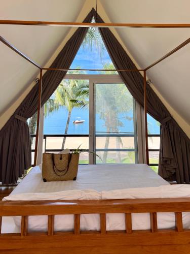 a bed in a tent with a view of the ocean at Tankini Beachfront Villa in Ban Khlong Son