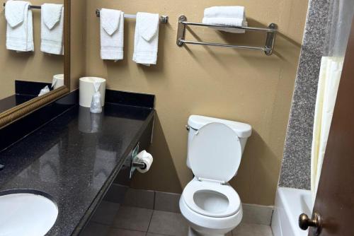 a bathroom with a toilet and a sink and towels at Broadway INN & SUITES OKC in Oklahoma City