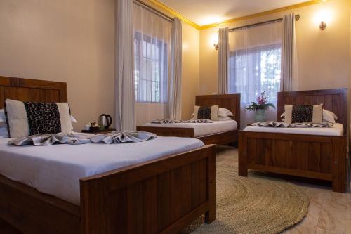 two beds in a room with two windows at Tulia Boutique Hotel & Spa in Arusha