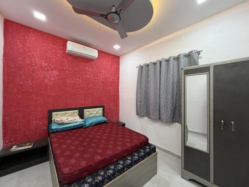 - une chambre dotée d'un mur rouge avec un lit et un miroir dans l'établissement Cozy Madh Island Cottage with Private Courtyard, à Jāmb