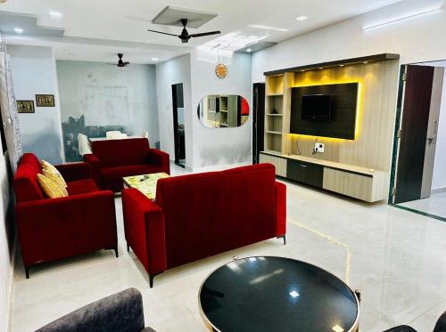 Il comprend un salon doté d'un mobilier rouge et d'une télévision à écran plat. dans l'établissement Cozy Madh Island Cottage with Private Courtyard, à Jāmb