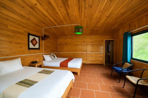 Un dormitorio con dos camas en una habitación con paredes de madera. en Muong Hoa Valley View Farmstay, en Sa Pa