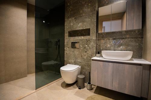 a bathroom with a toilet and a sink and a shower at Aether, Light Modern Living in Gaïtánion