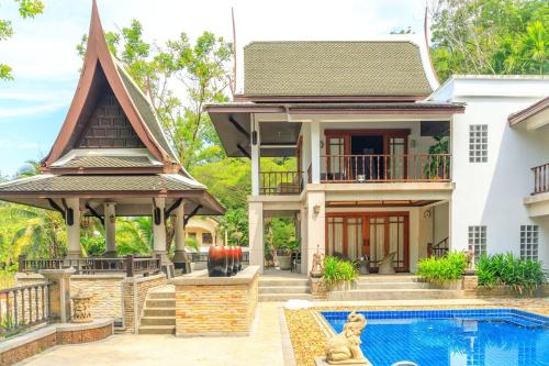 a home with a swimming pool and a house at Classic Cozy Thai Villa BIG pool Party OK in Patong Beach