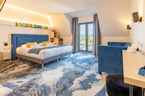 a bedroom with a large bed with a blue headboard at Brit Hotel, Spa & Restaurant - Colmar Est in Bischwihr