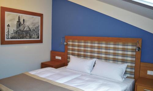 a bedroom with a bed with a blue wall at Hotel & Restaurant Waldcafe Hettstedt in Hettstedt