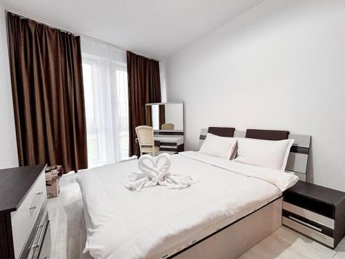 une chambre avec un grand lit blanc avec un nœud dessus dans l'établissement Julia Airport Apartment With Parking, à Someşeni
