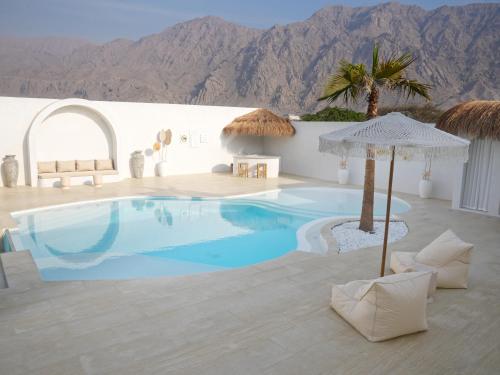 una piscina con sedie e ombrelloni in un resort di Pool Villa Daya a Ras al Khaimah