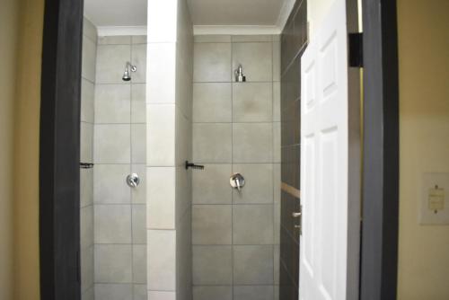 Un baño con ducha con puerta de cristal. en 41 on Clarendon, en Graskop