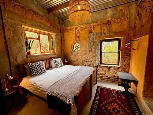a bedroom with a bed in a room with a stone wall at One Eye Dog in Koringberg