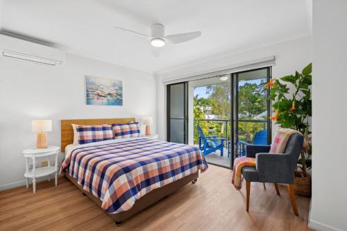 a bedroom with a bed and a chair and a window at Spacious, 2 bedroom Townhouse in Noosaville Resort in Noosaville