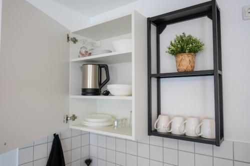 a kitchen with a shelf with dishes and a mirror at Kaisercity Apartment 2 in Nuremberg