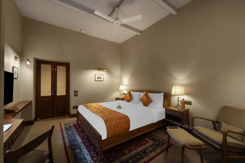 a bedroom with a bed and a desk and a chair at Kashe Benaras in Varanasi