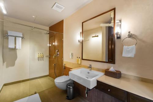 a bathroom with a sink and a toilet and a mirror at Kashe Benaras in Varanasi
