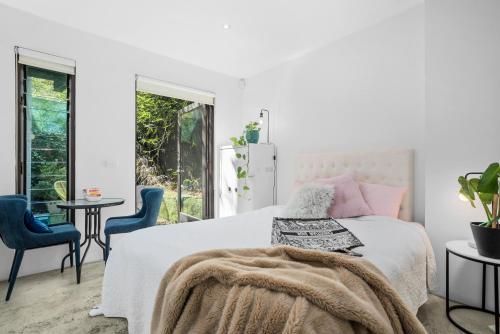 1 dormitorio blanco con 1 cama y 2 sillas azules en Melbourne suites - Zen Oasis or skyline views, en Melbourne