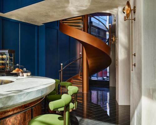 uma escada em espiral em um banheiro com bancos verdes em The George At Columbia Harlem, Tapestry Collection By Hilton em Nova Iorque