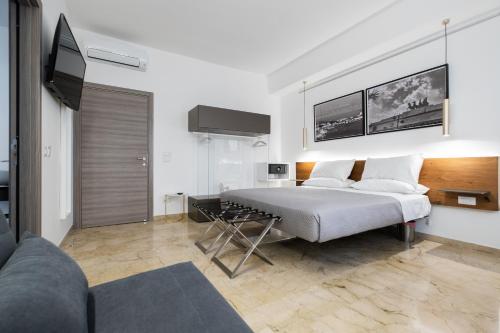 a white bedroom with a bed and a couch at Talìa Rooms and Gallery in Messina
