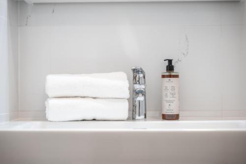 un lavabo de salle de bain avec des serviettes et une bouteille de savon dans l'établissement Majestic Square View Residence, à Prague