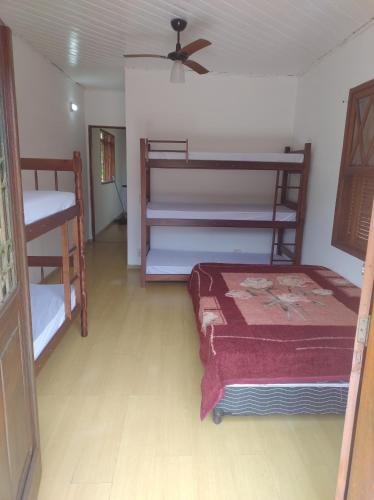 a bedroom with two bunk beds and a ceiling fan at Quarto na mansão ilhabela in Ilhabela