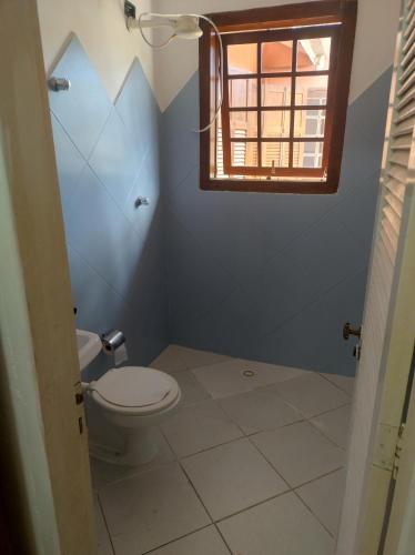 a bathroom with a toilet and a window at Quarto na mansão ilhabela in Ilhabela