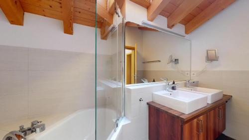 a bathroom with a tub and a sink and a shower at Abitaziun Allegra Sur DG - Zuoz in Zuoz