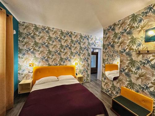a small bedroom with a bed and a wall with tropical wallpaper at AlCivico3 in Civitanova Marche