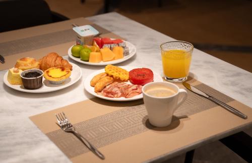 Four Points by Sheraton Chongqing في تشونغتشينغ: طاولة مع أطباق من الطعام وكأس من عصير البرتقال