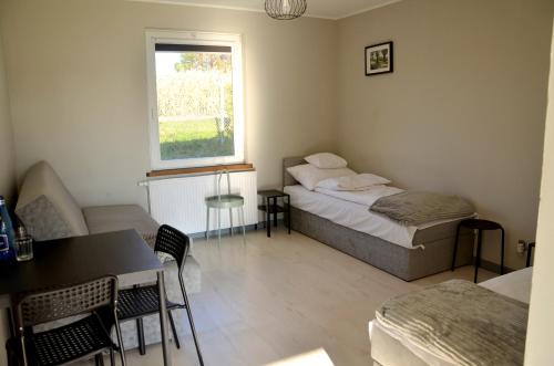 een slaapkamer met een bed, een tafel en een raam bij Hotelik nad jeziorem w Łasinie in Łasin