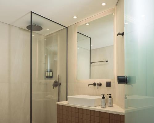 a bathroom with a sink and a shower with a mirror at Galaxy Suites Boutique Resort in Hersonissos